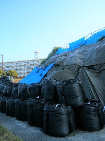 先日ご紹介した空自春日基地内の崖崩れ。その後このようにシートが掛けられ土嚢が積まれ、そして上にあったジェット戦闘機が消えてしまいました。たぶんあちこちの被災地の復旧支援を優先して、自分のところの本格復旧は後回しなのでしょうね。お疲れさまです。　それでもいつかはあの戦闘機、戻ってきて欲しいです。