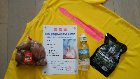 さて、今回の参加賞の数々です。Tシャツ背中のH-Ⅱロケットのシルエット、かっこいいでしょ？　ずっしり重たい安納芋もさることながら、大会記念ラベルのペットボトルは水ではなく芋焼酎です。そして右端は宇宙食のたこ焼き！　なかなかユニークですよね。